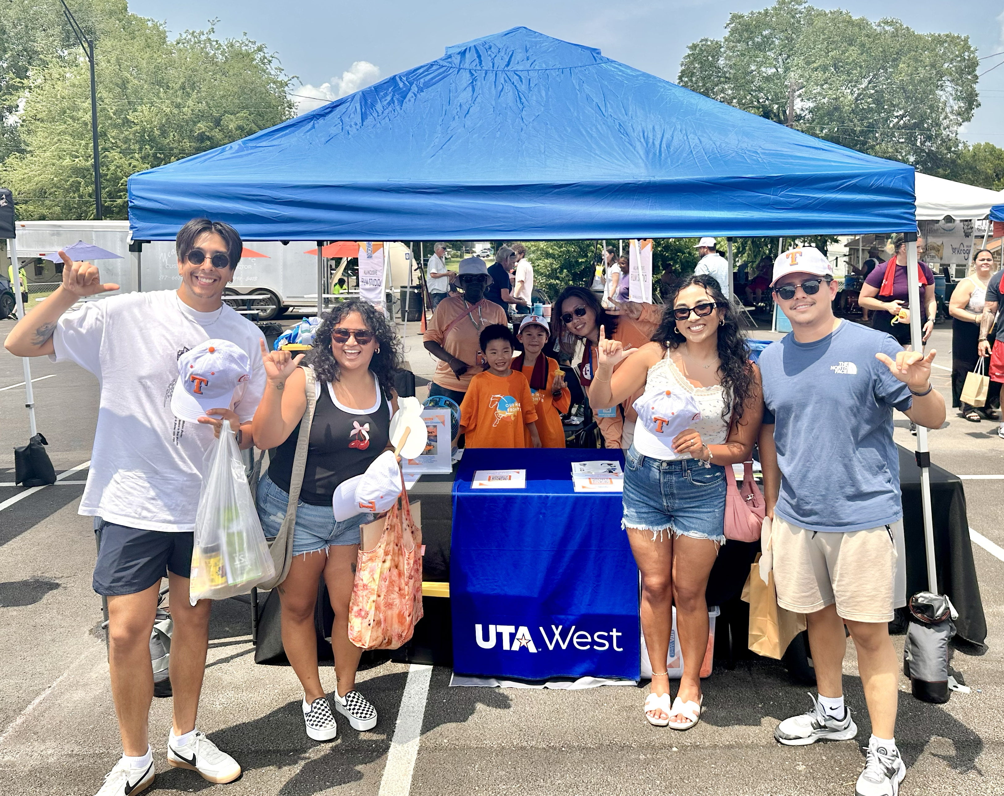students smiling in front of u t a west table